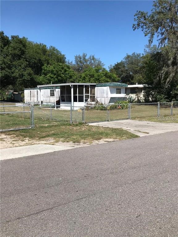 A single-story mobile home with a screened-in porch sits behind a chain-link fence — 274 SUNSET BLVD, POLK CITY, FL