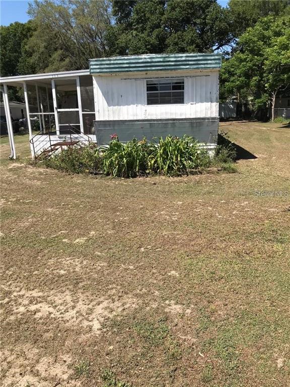 An exterior view of a weathered mobile home with an attached screened-in porch — 274 SUNSET BLVD, POLK CITY, FL
