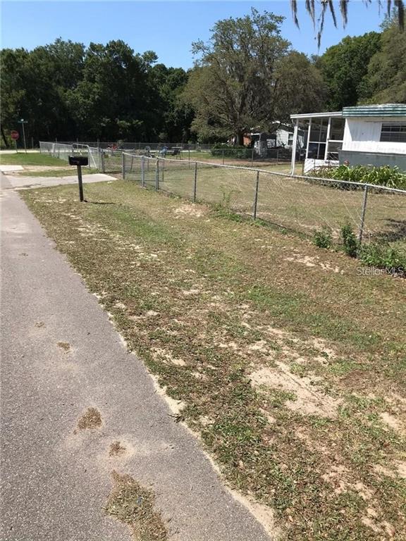 A paved road runs alongside a fenced yard with a mobile home in the background — 274 SUNSET BLVD, POLK CITY, FL