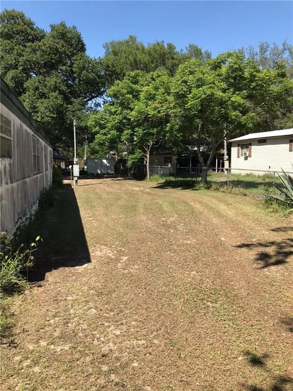 A grassy yard sits between two mobile homes under a canopy of mature trees — 274 SUNSET BLVD, POLK CITY, FL