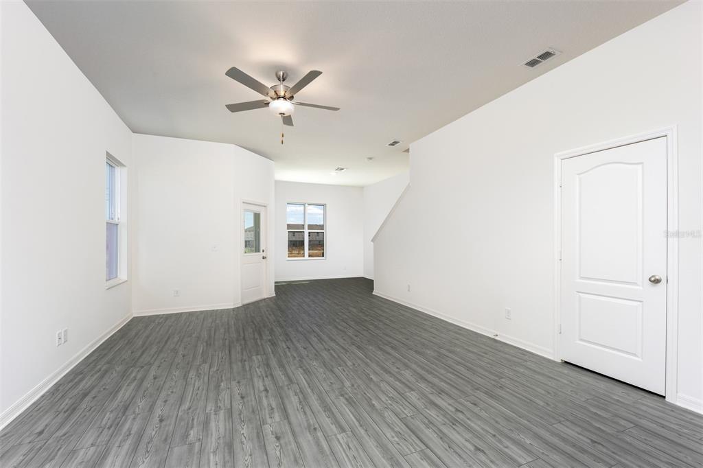 An empty room with white walls, gray wood-look flooring, a ceiling fan, and two doors — 678 POPPY LANE, DUNDEE, FL