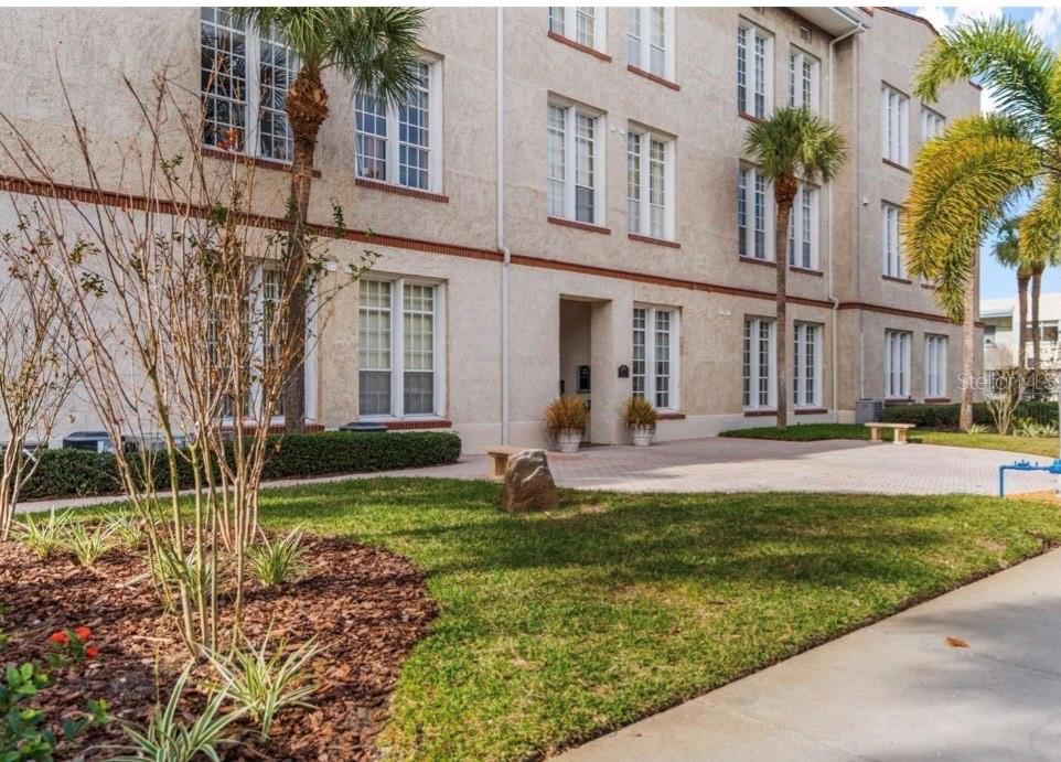 A multi-story stucco apartment building with palm trees and a paved courtyard entrance — 701 MIRROR LAKE DRIVE N UNIT 317, ST PETERSBURG, FL