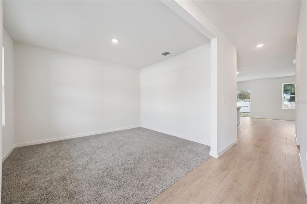A room with gray carpet transitions to a hallway with light wood-look flooring — 1139 GULL DRIVE, APOPKA, FL
