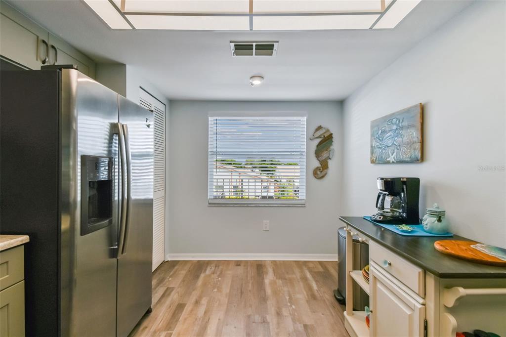 A kitchen features stainless steel appliances, light wood-look flooring, and a coffee station — 7301 29TH AVE DR W UNIT 202, BRADENTON, FL