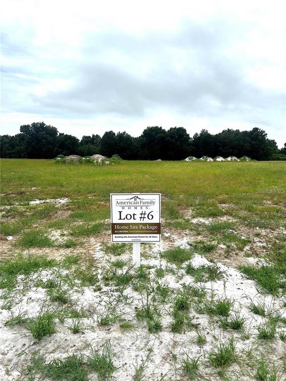 A sign for American Family Homes stands on a vacant, grassy lot with trees behind — 38797 RANCH GATE BOULEVARD, UMATILLA, FL