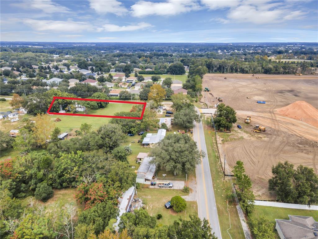 An aerial view shows a rectangular property outlined in red next to a construction site — 2502 SCHOPKE ROAD, APOPKA, FL