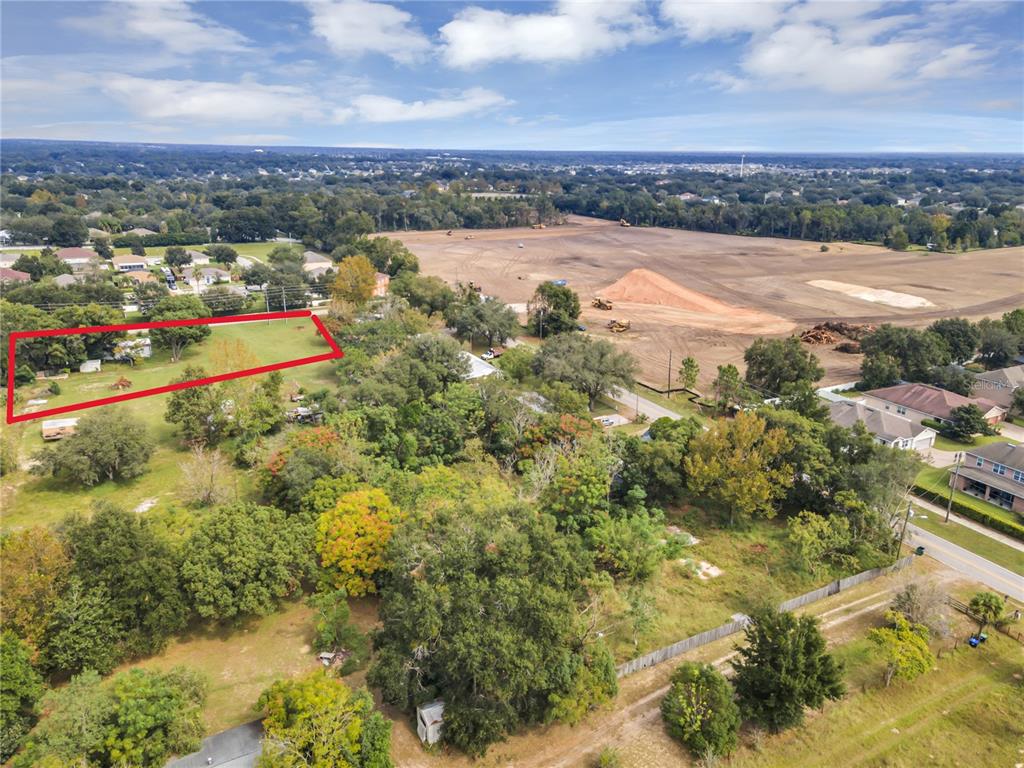An aerial view shows a rectangular property outlined in red next to a construction site — 2502 SCHOPKE ROAD, APOPKA, FL