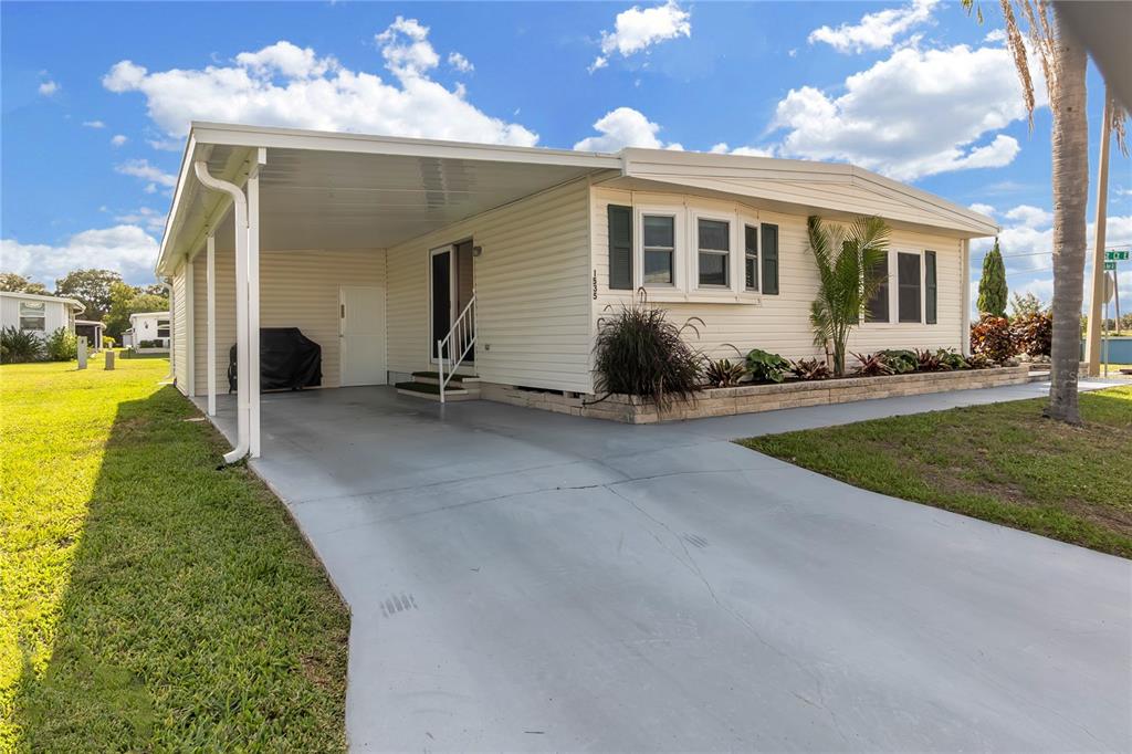 A single-story manufactured home with a carport, light siding, and a concrete driveway — 1535 45TH AVENUE DRIVE E, ELLENTON, FL
