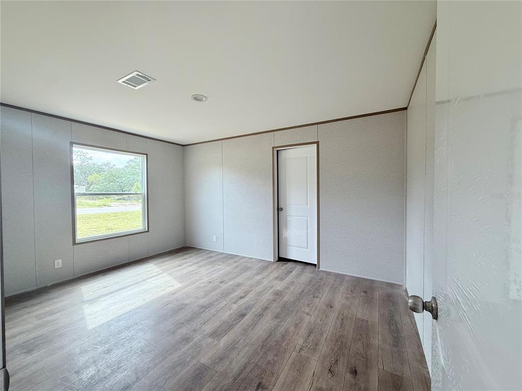 An open-concept kitchen and living area features light-colored walls and wood-look flooring — 6470 NE 115TH AVENUE, WILLISTON, FL