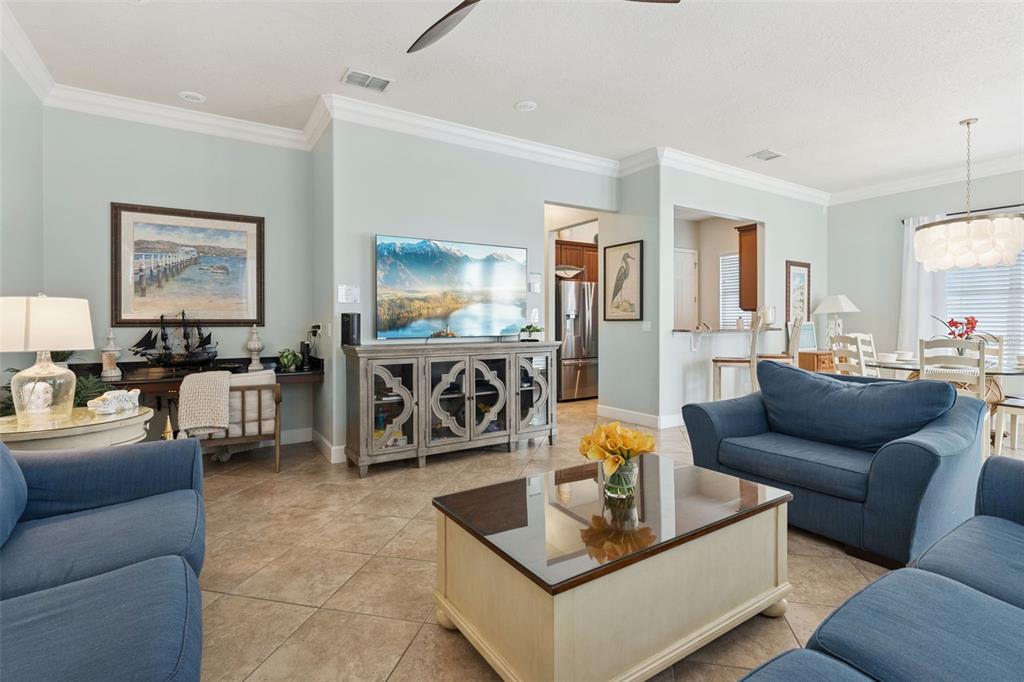 A living room with blue sofas, a glass-topped coffee table, and a wall-mounted television — 1440 FAIRVIEW CIRCLE, KISSIMMEE, FL