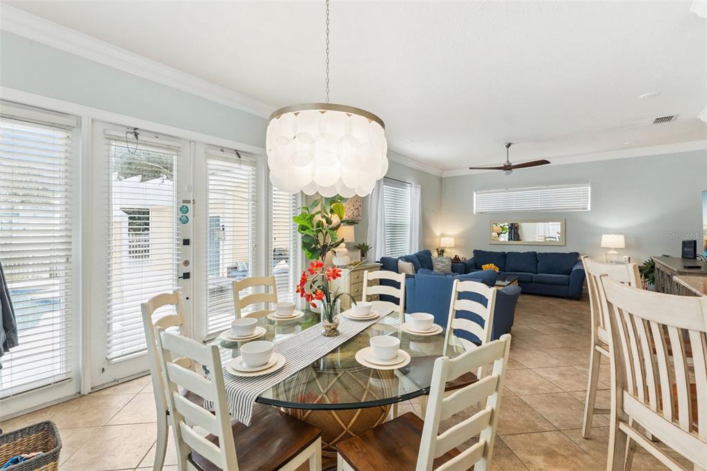 A dining area with a glass table and chandelier opens into a blue-furnished living room — 1440 FAIRVIEW CIRCLE, KISSIMMEE, FL