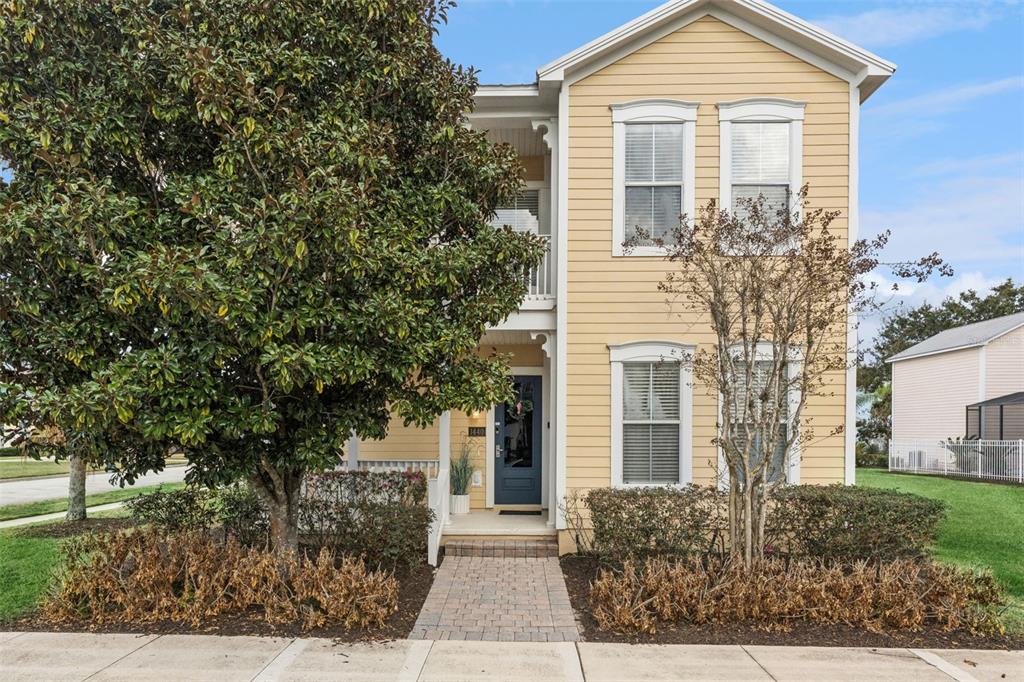 A two-story yellow house with a front porch, brick walkway, and large trees — 1440 FAIRVIEW CIRCLE, KISSIMMEE, FL