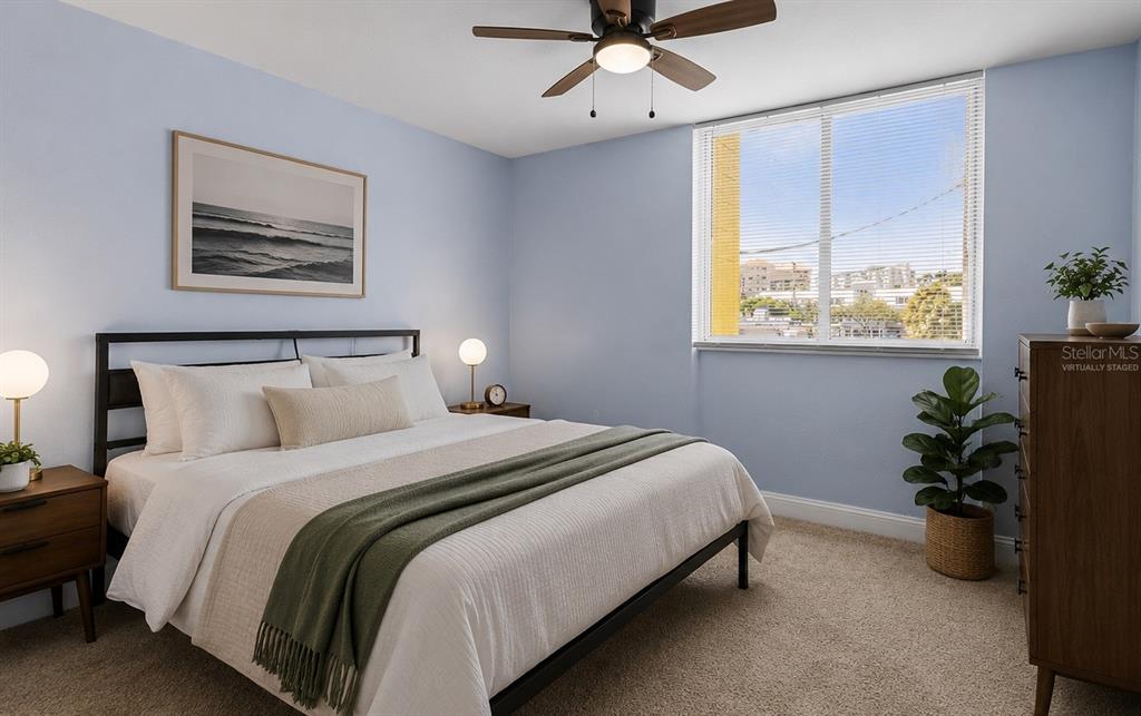 A bedroom with light blue walls, a bed, a ceiling fan, and a window view — 1301 S HOWARD AVENUE UNIT B18, TAMPA, FL