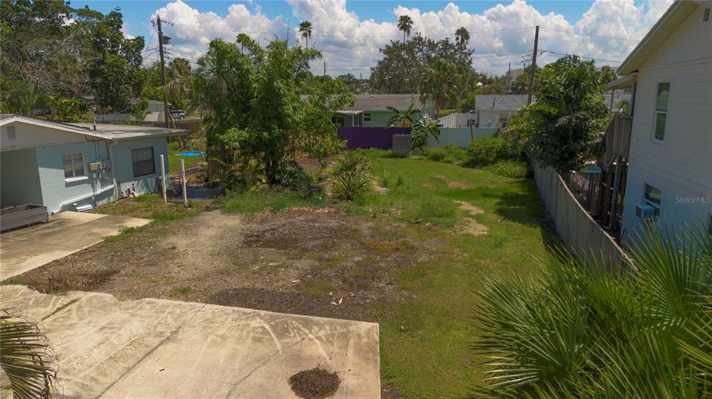 An elevated view of a grassy backyard between two houses with a concrete patio area — HELENA STREET NE, ST PETERSBURG, FL