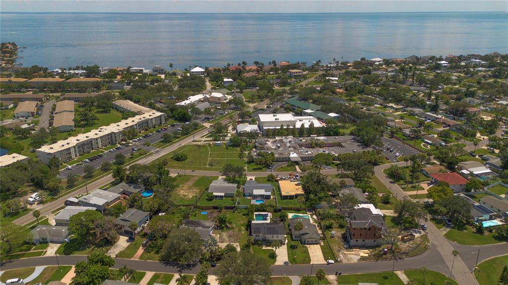 An aerial view shows a coastal neighborhood with houses, apartment buildings, and a large body of water — HELENA STREET NE, ST PETERSBURG, FL
