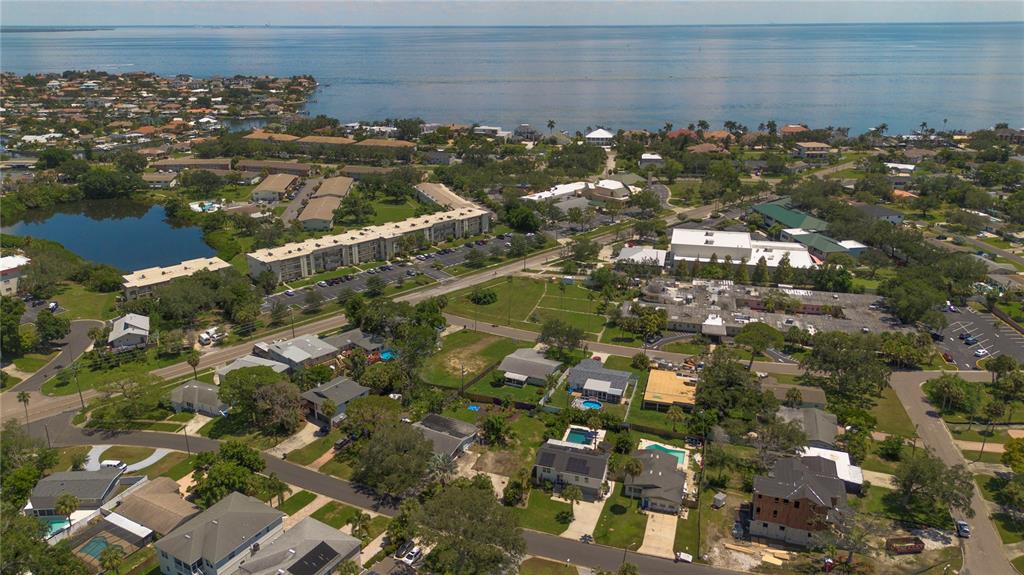 An aerial view shows a coastal neighborhood with houses, apartment complexes, and a nearby bay — HELENA STREET NE, ST PETERSBURG, FL