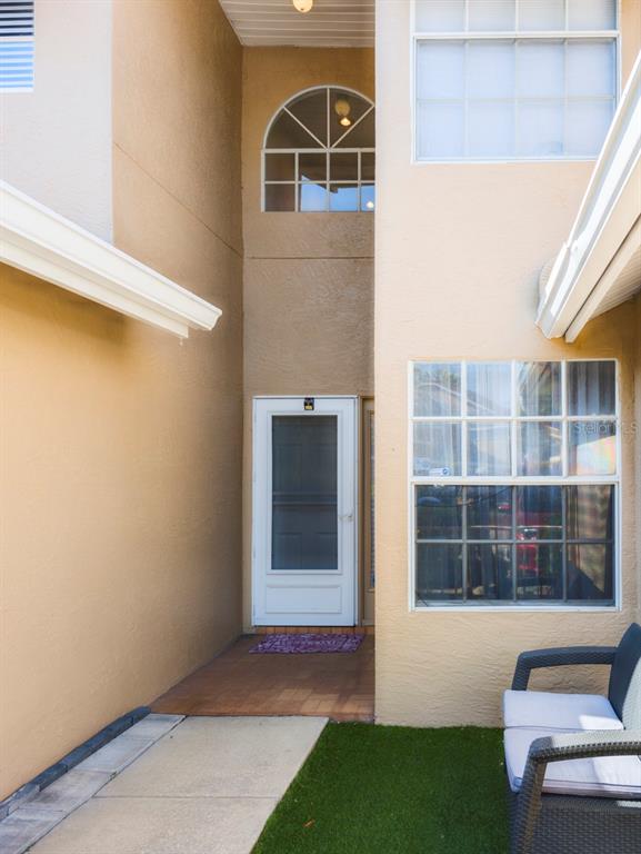A tan stucco building exterior features a recessed front entrance with a screen door — 3077 BRANCH DRIVE, CLEARWATER, FL