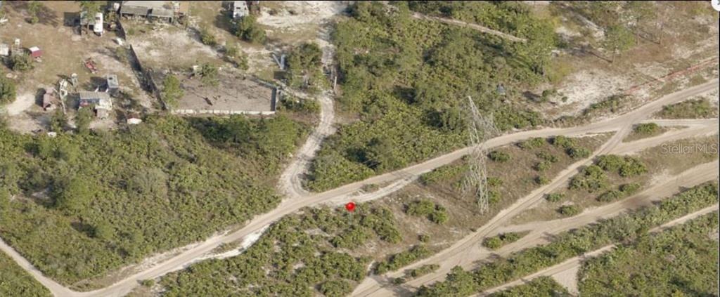 An aerial view shows a dirt road, a power line tower, and undeveloped brushy land — HOLOPAW GROVES ROAD, ST CLOUD, FL