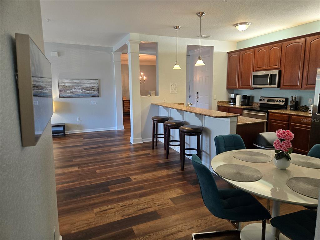 An open-concept kitchen with a breakfast bar, dining area, and wood-look flooring — 5049 SHOREWAY LOOP UNIT 30101, ORLANDO, FL