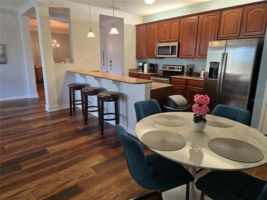 A kitchen with wood cabinets, stainless steel appliances, and a breakfast bar with three stools — 5049 SHOREWAY LOOP UNIT 30101, ORLANDO, FL