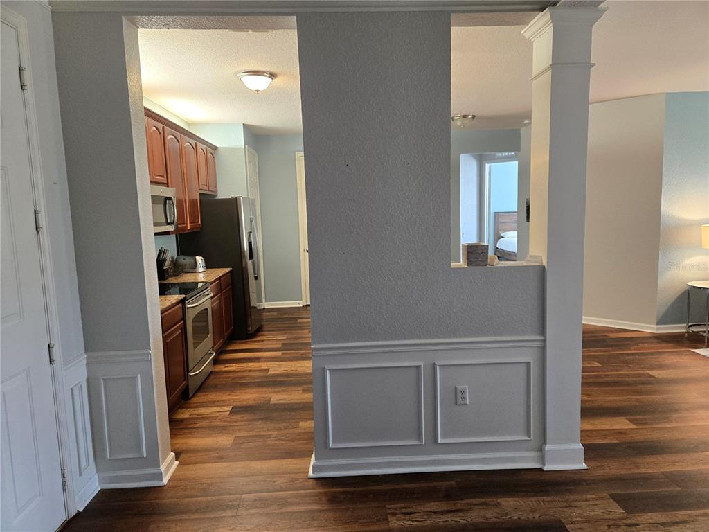 A kitchen with wood cabinets and stainless appliances is visible through a wall opening — 5049 SHOREWAY LOOP UNIT 30101, ORLANDO, FL
