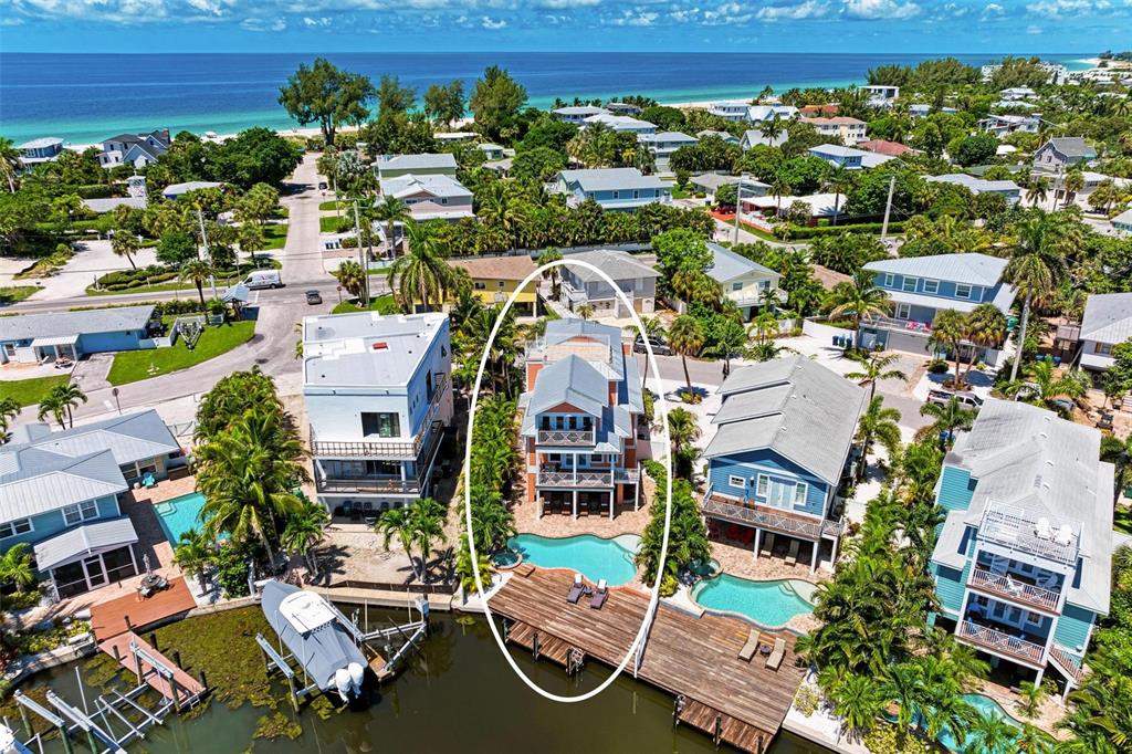 An aerial view shows a multi-story house with a pool and dock on a canal — 203 N HARBOR DRIVE, HOLMES BEACH, FL