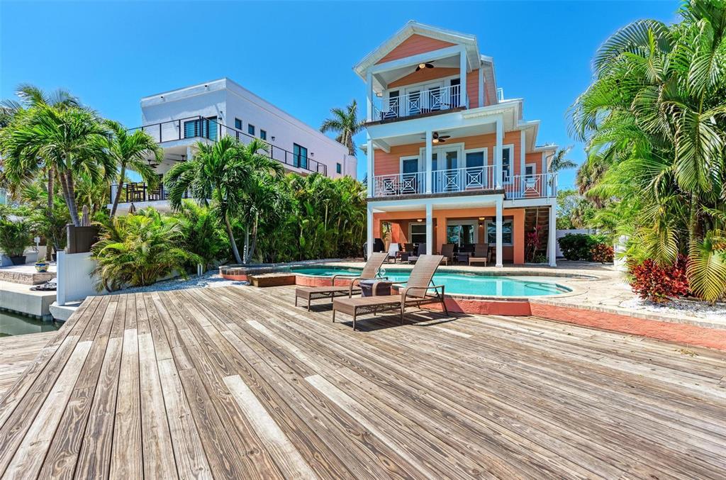 A three-story peach-colored house features a swimming pool and a large wooden deck — 203 N HARBOR DRIVE, HOLMES BEACH, FL