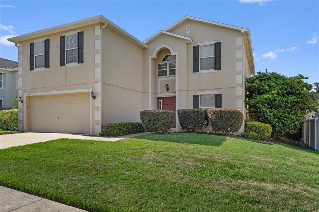 A two-story suburban house with a beige stucco exterior, a two-car garage, and landscaping — 14308 NW 161ST AVENUE, ALACHUA, FL