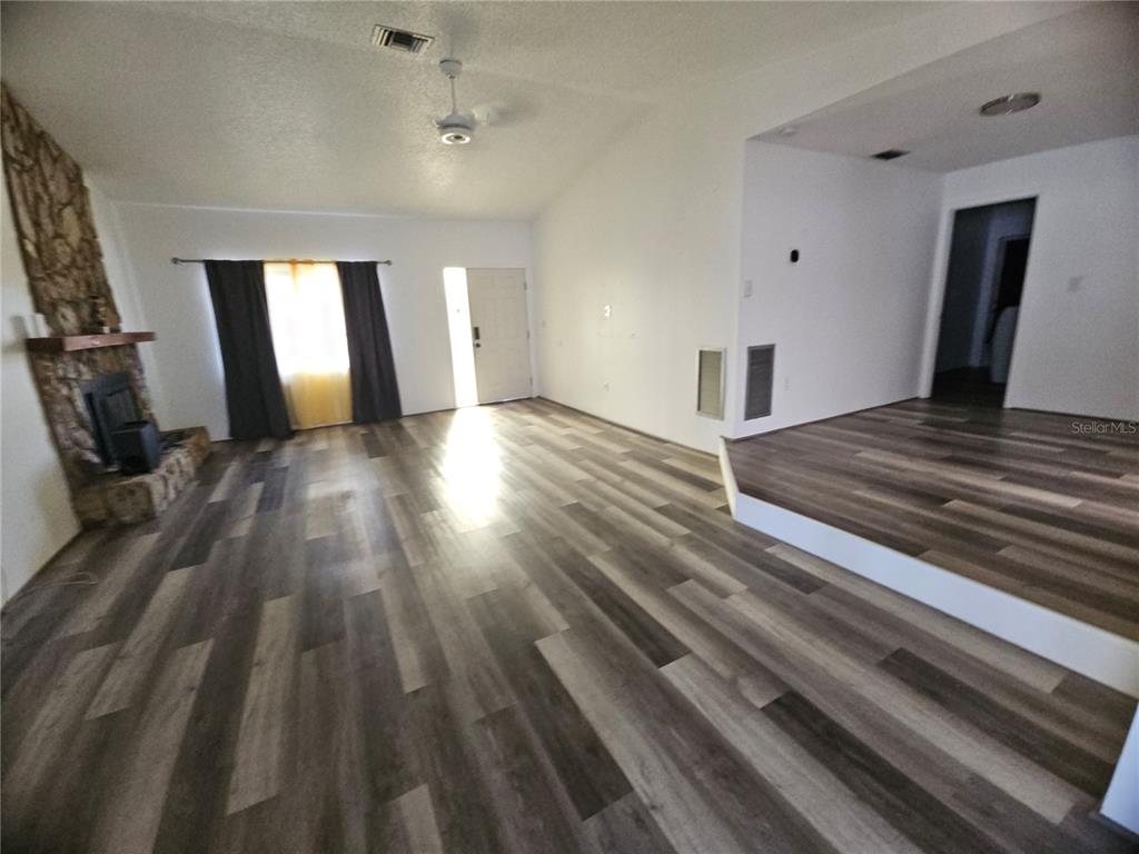A living room features wood-look flooring, a stone fireplace, and a raised platform area — 11557 124TH TERRACE, LARGO, FL