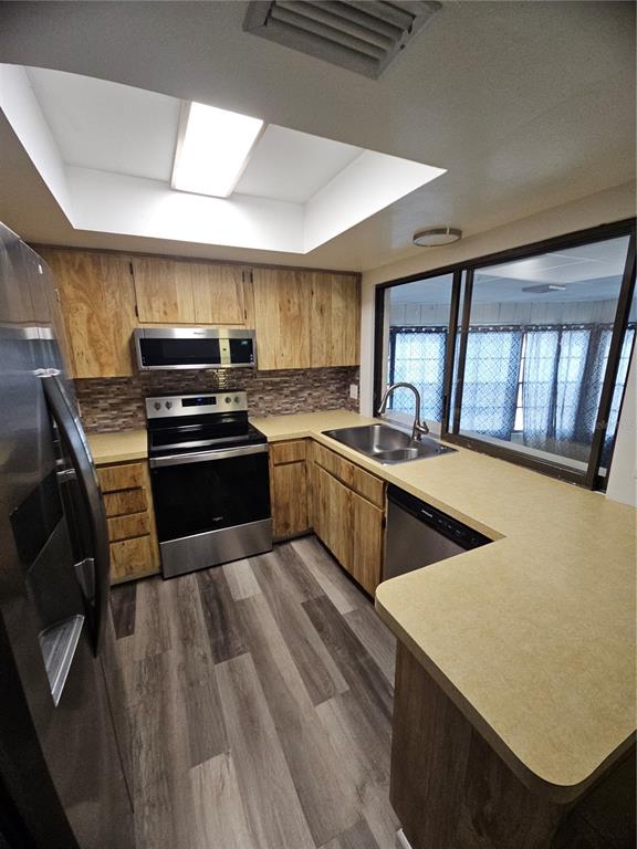 A kitchen with wood cabinets, stainless steel appliances, a tile backsplash, and a skylight — 11557 124TH TERRACE, LARGO, FL
