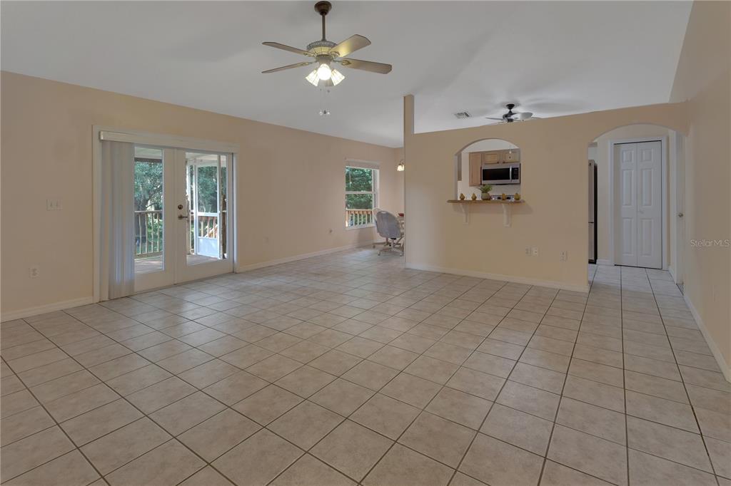 An open-concept living area features light-colored tile flooring, a ceiling fan, and a kitchen pass-through — 2249 HONTOON ROAD, DELAND, FL