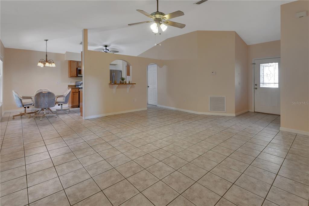 A spacious living area with tile flooring, a ceiling fan, and an open kitchen pass-through — 2249 HONTOON ROAD, DELAND, FL