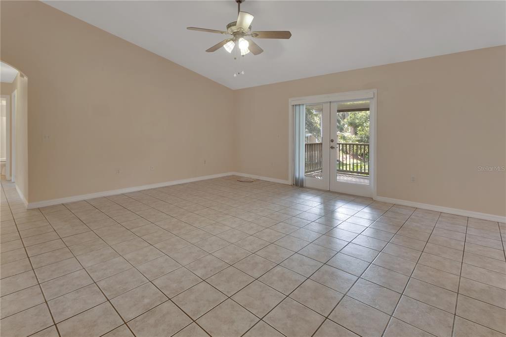 An empty room features beige walls, light-colored tile flooring, a ceiling fan, and glass doors — 2249 HONTOON ROAD, DELAND, FL