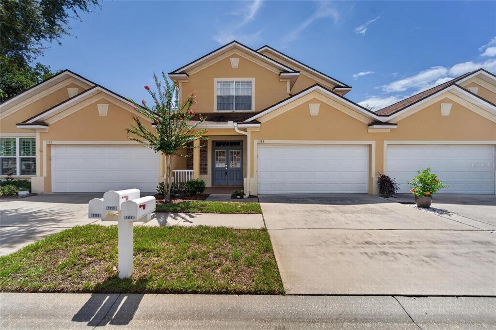A two-story tan townhouse with a white garage door and a shared mailbox in front — 1113 SAVANNAH LANDINGS AVENUE, VALRICO, FL