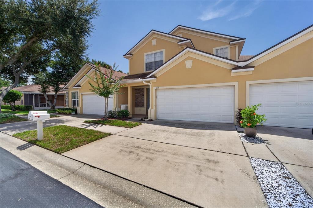 A two-story tan townhouse with a two-car garage and a concrete driveway — 1113 SAVANNAH LANDINGS AVENUE, VALRICO, FL