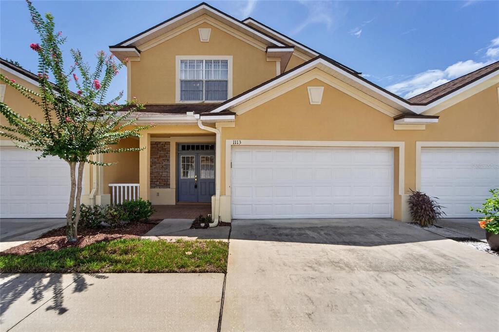 A two-story house with a yellow stucco exterior, a two-car garage, and a front entrance — 1113 SAVANNAH LANDINGS AVENUE, VALRICO, FL