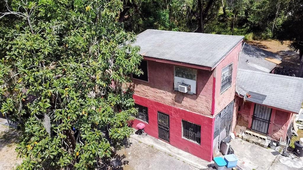 An aerial view of a two-story pink stucco house with a metal roof and trees — 6981 HOLLY STREET, MOUNT DORA, FL