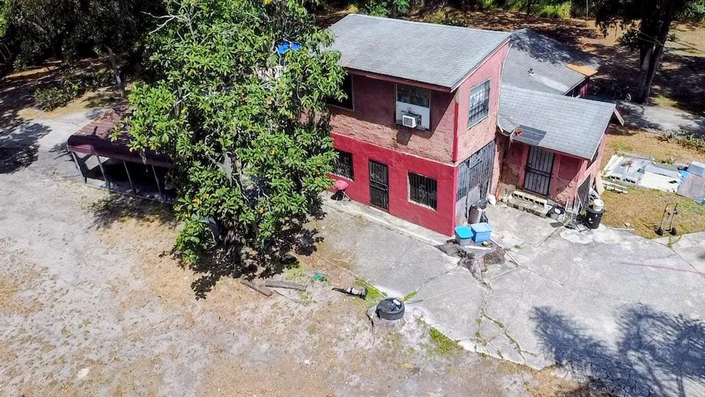 An aerial view of a two-story red house with a large tree and concrete yard — 6981 HOLLY STREET, MOUNT DORA, FL