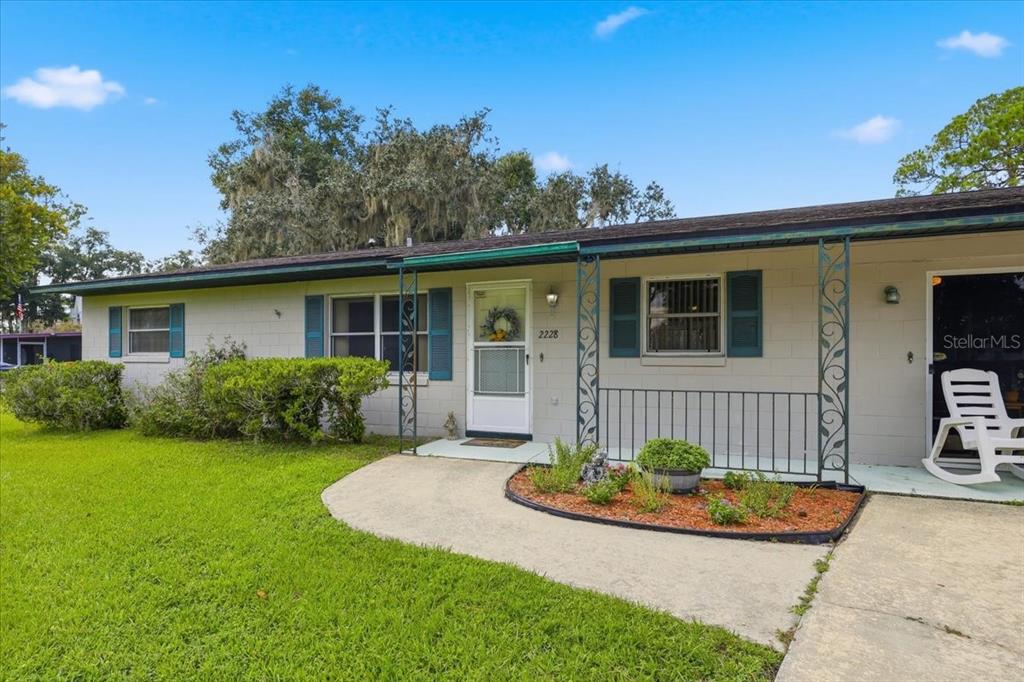 A single-story house with a white concrete block exterior, green shutters, and a front porch — 2228 RIVER RIDGE ROAD, DELAND, FL