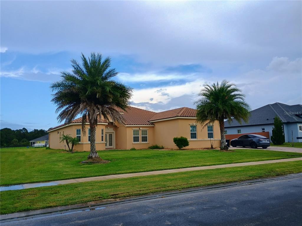 A single-story tan house with a tiled roof and two palm trees in the front yard — 4394 PRESERVATION CIRCLE, MELBOURNE, FL