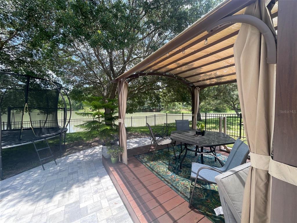 A backyard patio features a wooden deck with a gazebo, dining set, and a trampoline — 4522 LISETTE CIRCLE, BROOKSVILLE, FL
