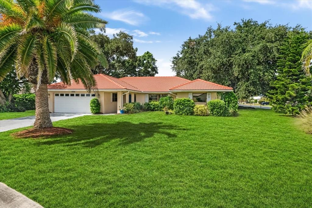 A single-story house with a red tile roof and a large palm tree in front — 1608 BOB O LINK DRIVE, VENICE, FL