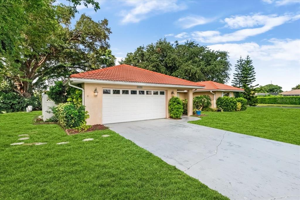 A single-story house with a red tile roof, white garage door, and a concrete driveway — 1608 BOB O LINK DRIVE, VENICE, FL