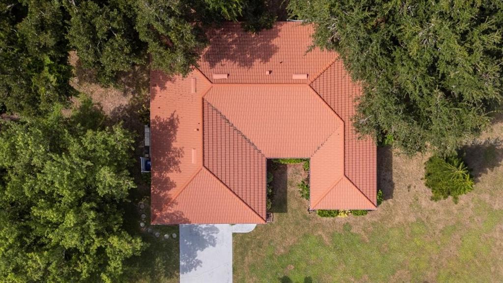 An aerial view shows a house with a red tile roof surrounded by trees — 1608 BOB O LINK DRIVE, VENICE, FL