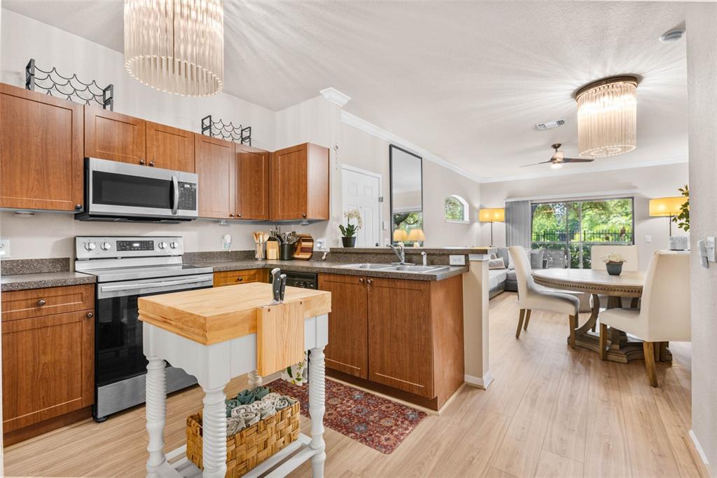 A kitchen with wood cabinets and a central island opens into a dining area — 2176 PORTOFINO PLACE UNIT 6-2612, PALM HARBOR, FL