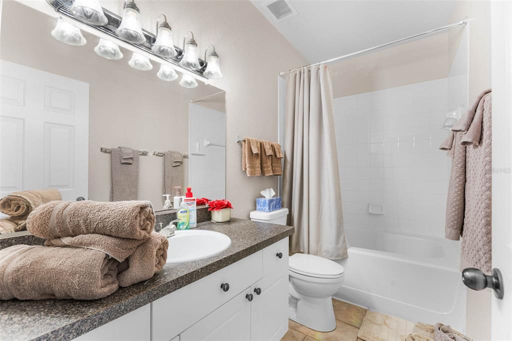 A bathroom features a white vanity with a dark countertop, a mirror, and a tub-shower — 2176 PORTOFINO PLACE UNIT 6-2612, PALM HARBOR, FL