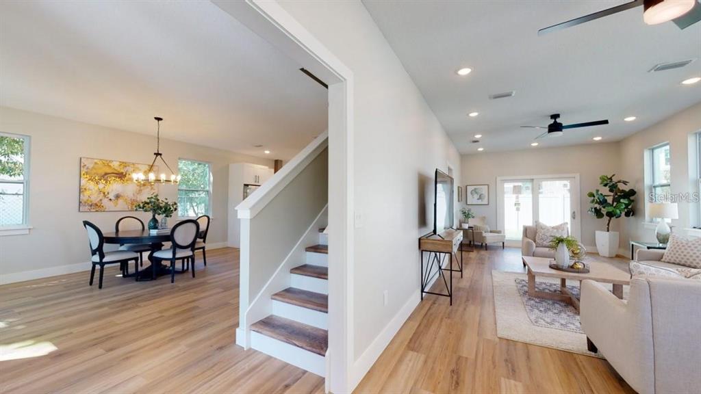 An open-concept living and dining area features light wood flooring and a central staircase — 5101 12TH AVENUE N, ST PETERSBURG, FL