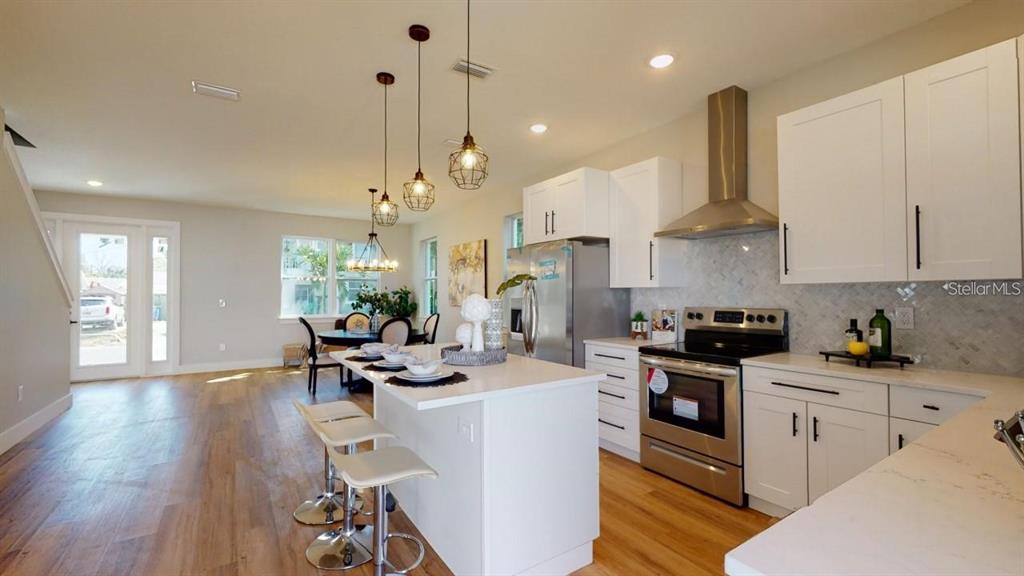 A modern kitchen features white cabinetry, stainless steel appliances, and a central island with stools — 5101 12TH AVENUE N, ST PETERSBURG, FL
