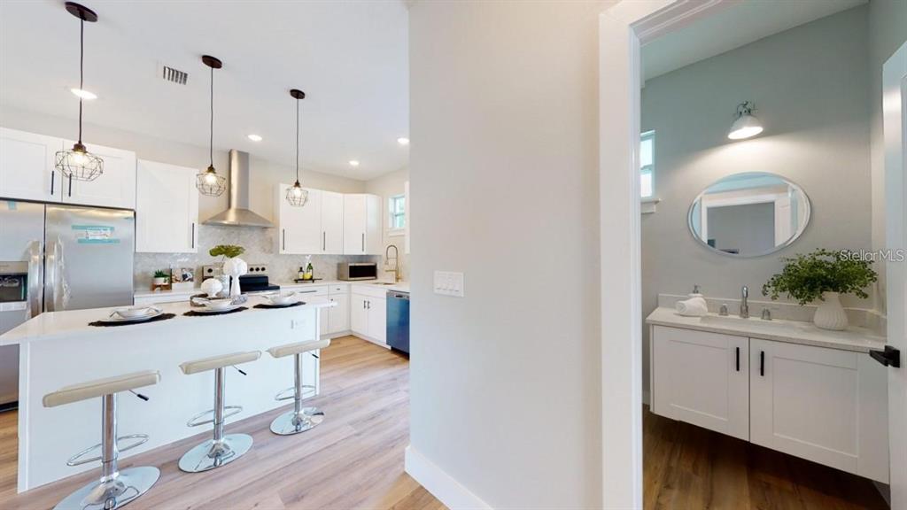 A kitchen with white cabinets and a breakfast bar next to a small bathroom — 5101 12TH AVENUE N, ST PETERSBURG, FL