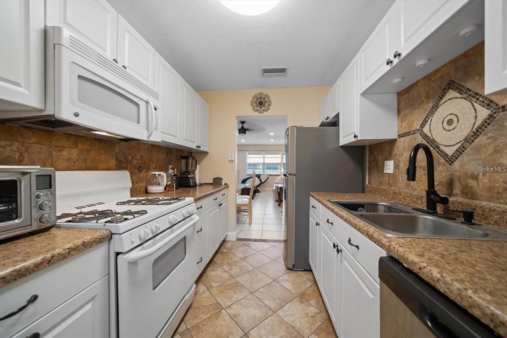 A living and dining area with tile floors, a glass-top table, and a white sofa — 10038 62ND TERRACE N UNIT 17, ST PETERSBURG, FL